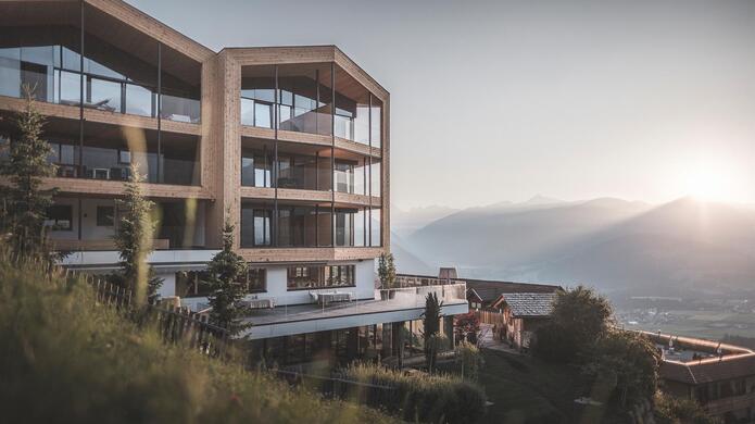 Das Berghotel Zirm bei untergehender Sonne mit Bergen im Hintergrund.