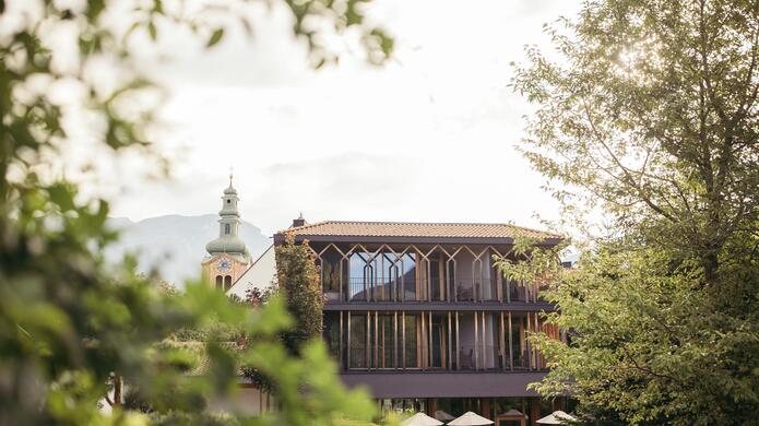 Gebäudeansicht des Hotel Engels Park, teilweise von Bäumen eingerahmt, mit Balkon und grüner Umgebung im Hintergrund.