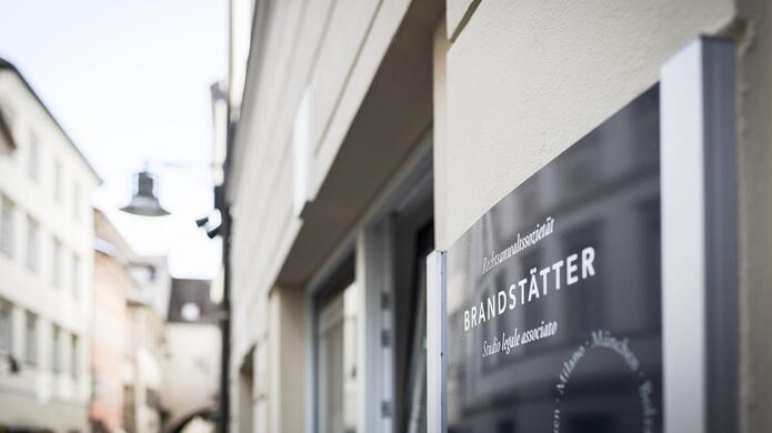 Primo piano della targhetta con il nome dello studio legale Brandstätter su uno sfondo sfocato.