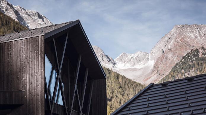Modernes Amus Chalets mit massiver Berglandschaft und blauem Himmel im Hintergrund.