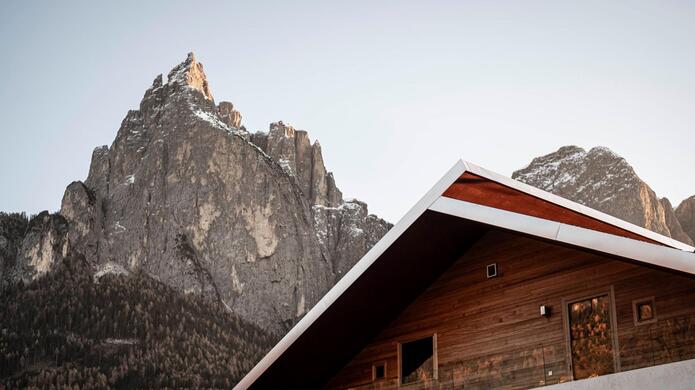 Hotel La Paula in alpiner Landschaft mit markanter Bergkulisse im Hintergrund und bewölktem Himmel.